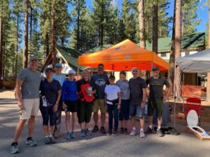A group of people gathered around an informational booth in a forested area